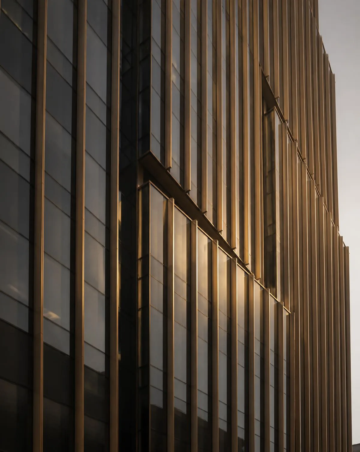 Fachada corporativa vista de baixo, com montantes verticais em bronze e vidro escuro